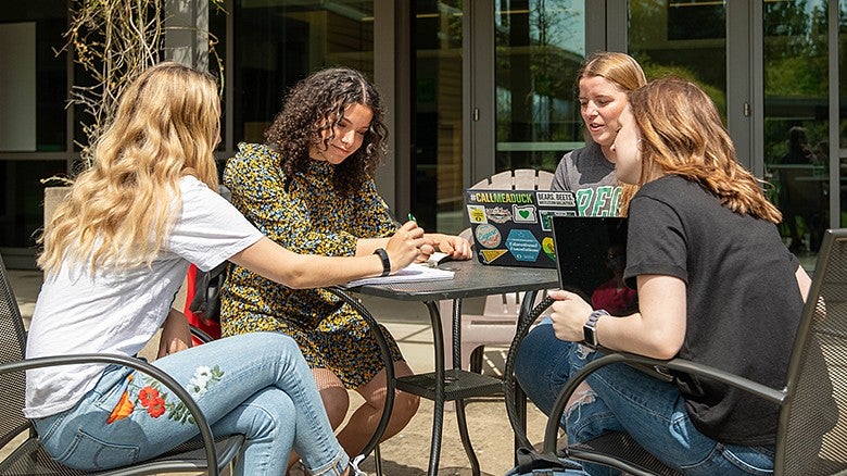 group of students sitting at a table outside of HEDCO