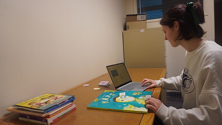 person sitting at table looking at a book