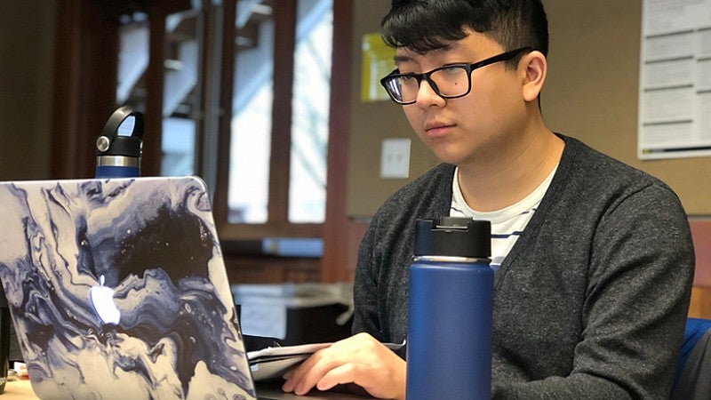 CDS Grad Student working on an open laptop