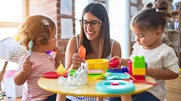 image of an individual with two children at a table playing with colored blocks