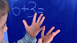 child adding six plus three using their hands